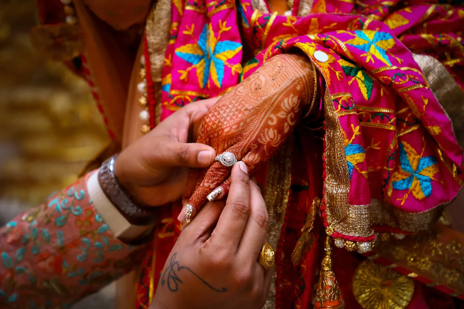 Bride's hennaed hands as the groom slips on the engagement ring — Nikhil Studio Production, Mangaluru